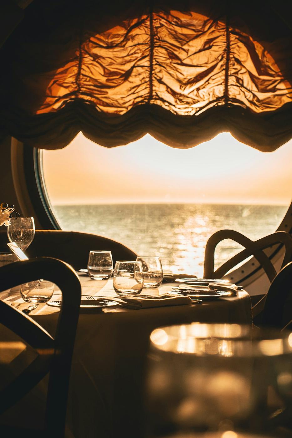 Coucher de soleil sur la mer vu à travers un hublot, tables dressées