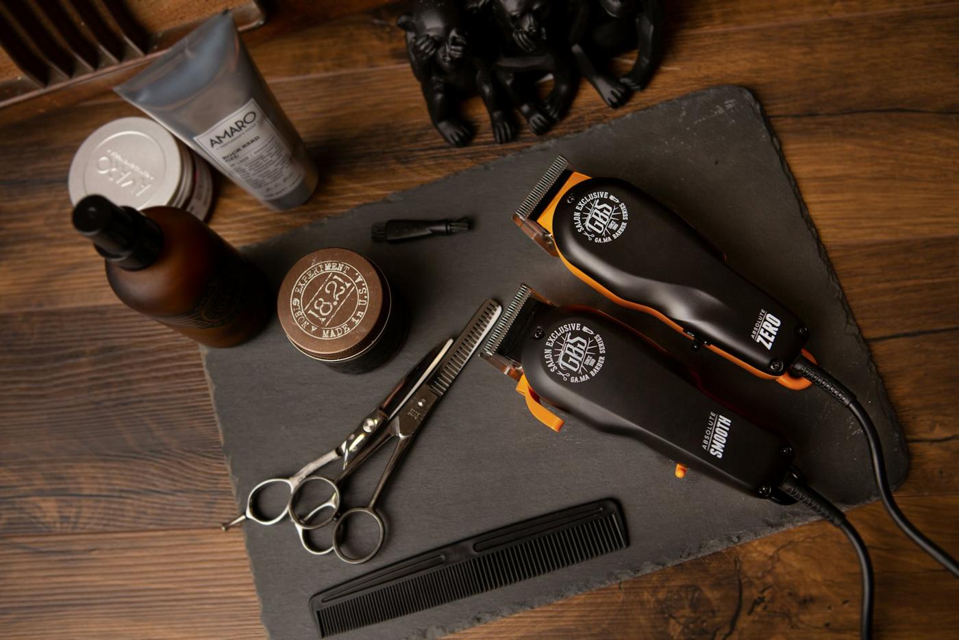 Tondeuses, ciseaux, peigne et produits sur une ardoise